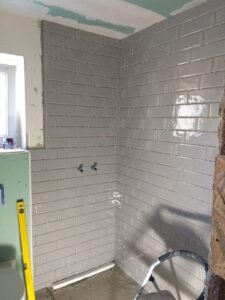 Verlegung von grauen Metrofliesen bei einer Badsanierung in Heidelberg inklusive bodengleiche Dusche - Gesamtansicht raumhohe Wandfliesen