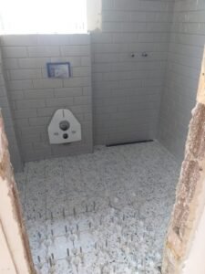 Verlegung von grauen Metrofliesen bei einer Badsanierung in Heidelberg inklusive bodengleiche Dusche