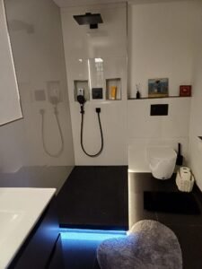 Komplettsanierung eines Bades in Heidelberg - Verlegung von Großformat-Wandfliesen in Weiß - Schwarze Duschwanne mit indirekter Beleuchtung