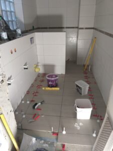 Umfassende Fliesenarbeiten in einem Bad in Ludwigshafen - Verlegung von grauen Bodenfliesen